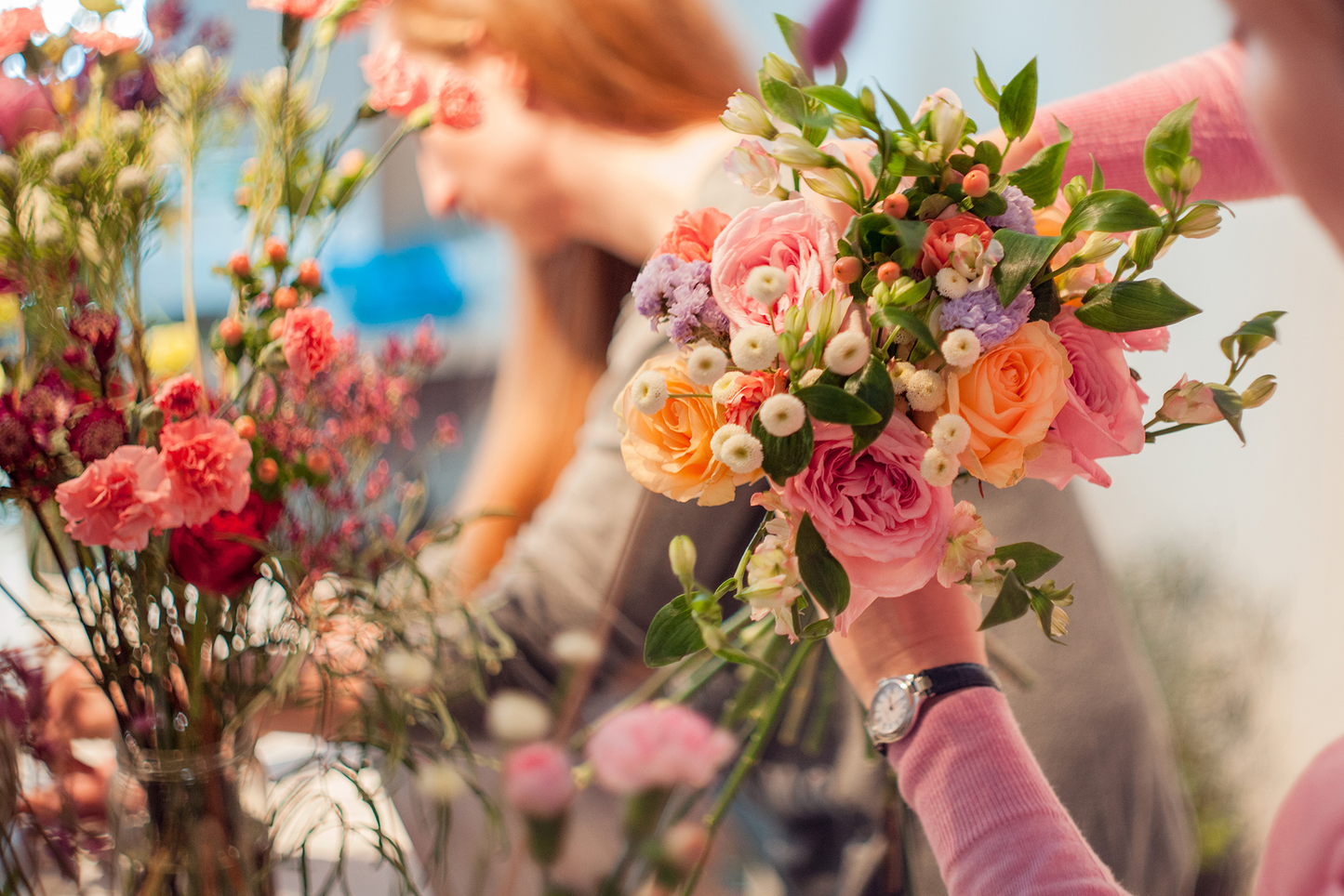 Two women building a  colorful flower bouquets against a blurred background
