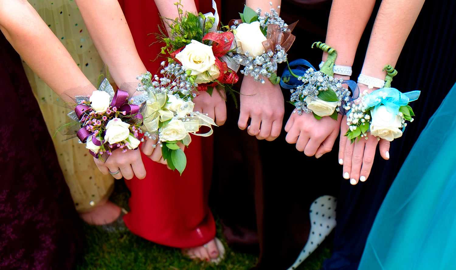 Hands holding colorful flower corsages in a circle