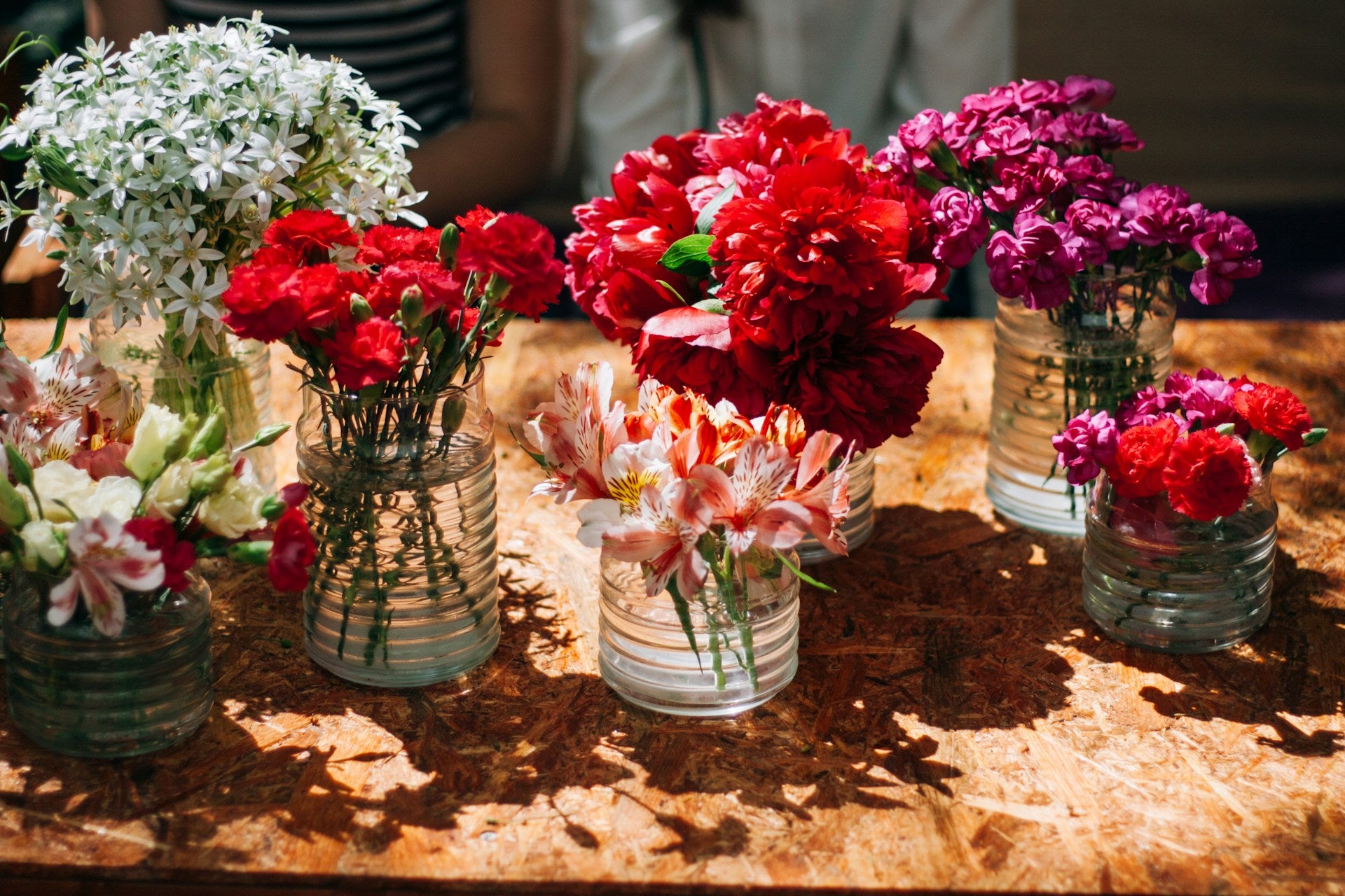 Assorted flowers in small vases on a wooden surface
