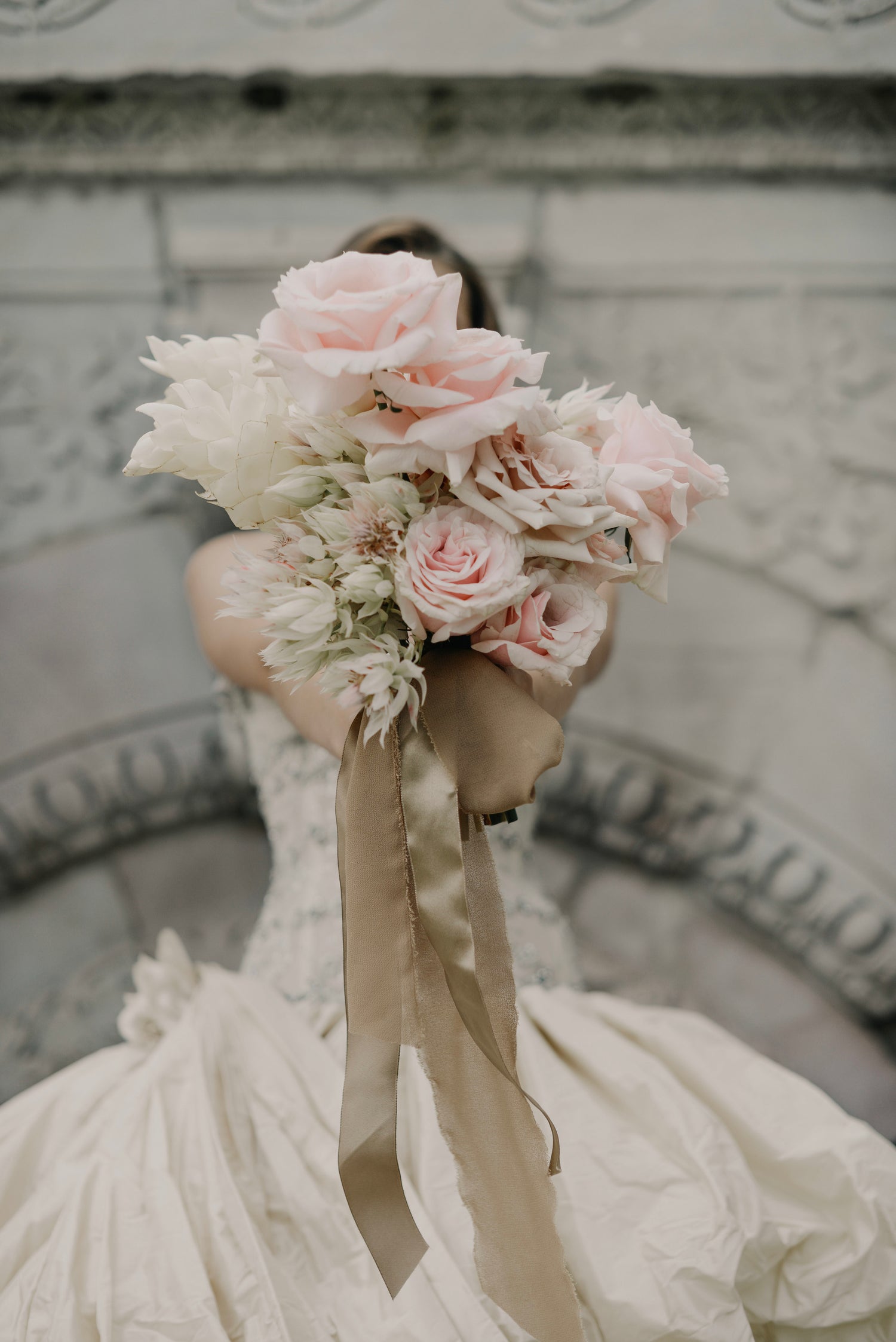 A bride holding a bouquet towards the camera  